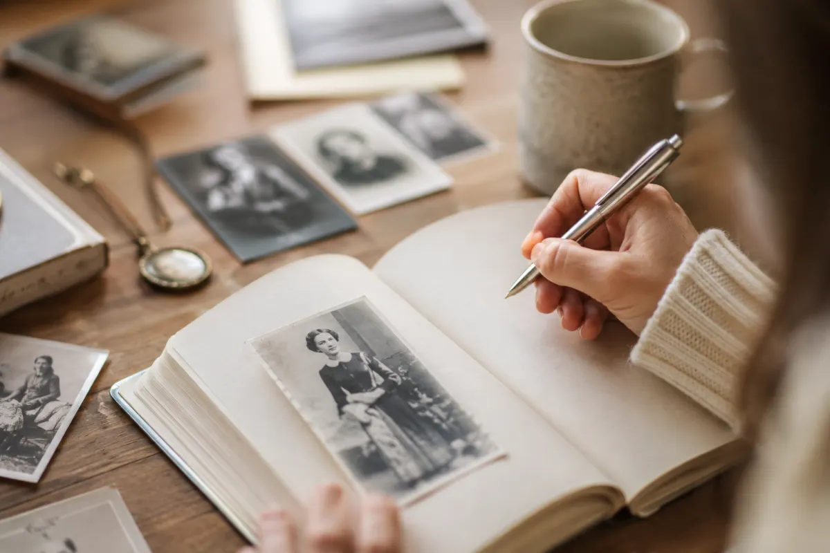 Gros plan sur la main de Sandrine écrivant un prénom à l'encre noire sur du papier antique